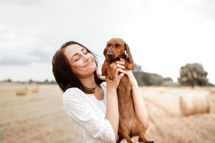 Smiling woman holding dog with love.